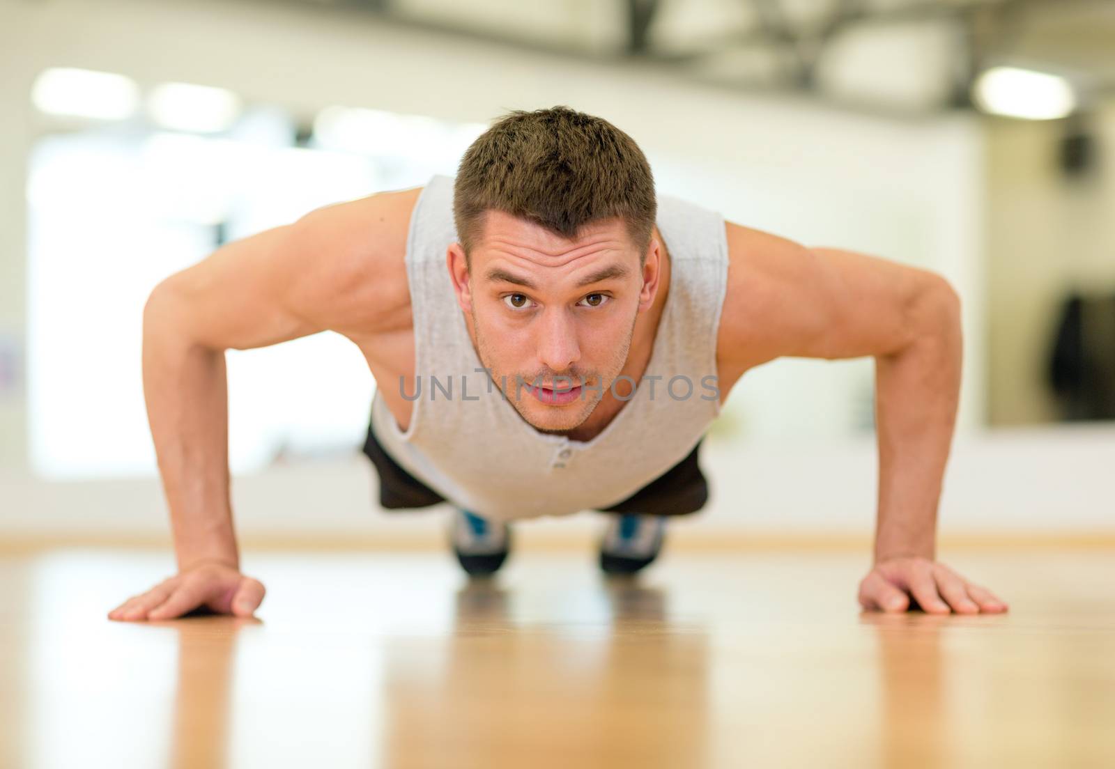 concentrated man doing push-ups in the gym by dolgachov