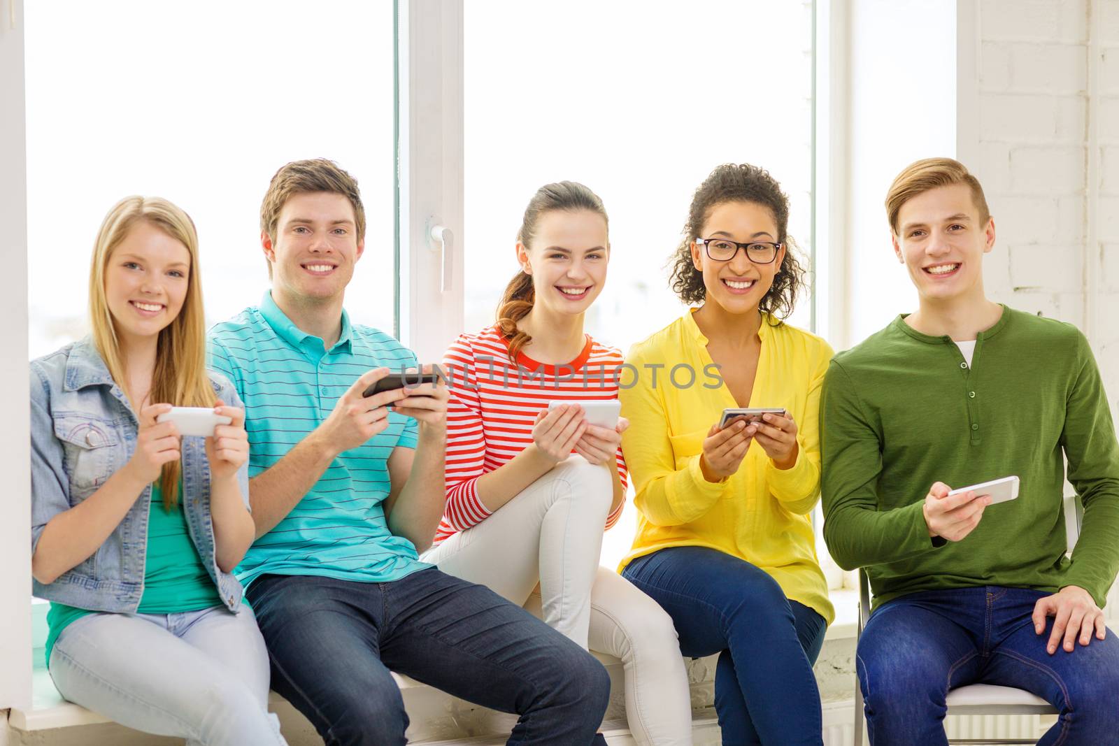 education, school and technology concept - smiling students with smartphone texting at school