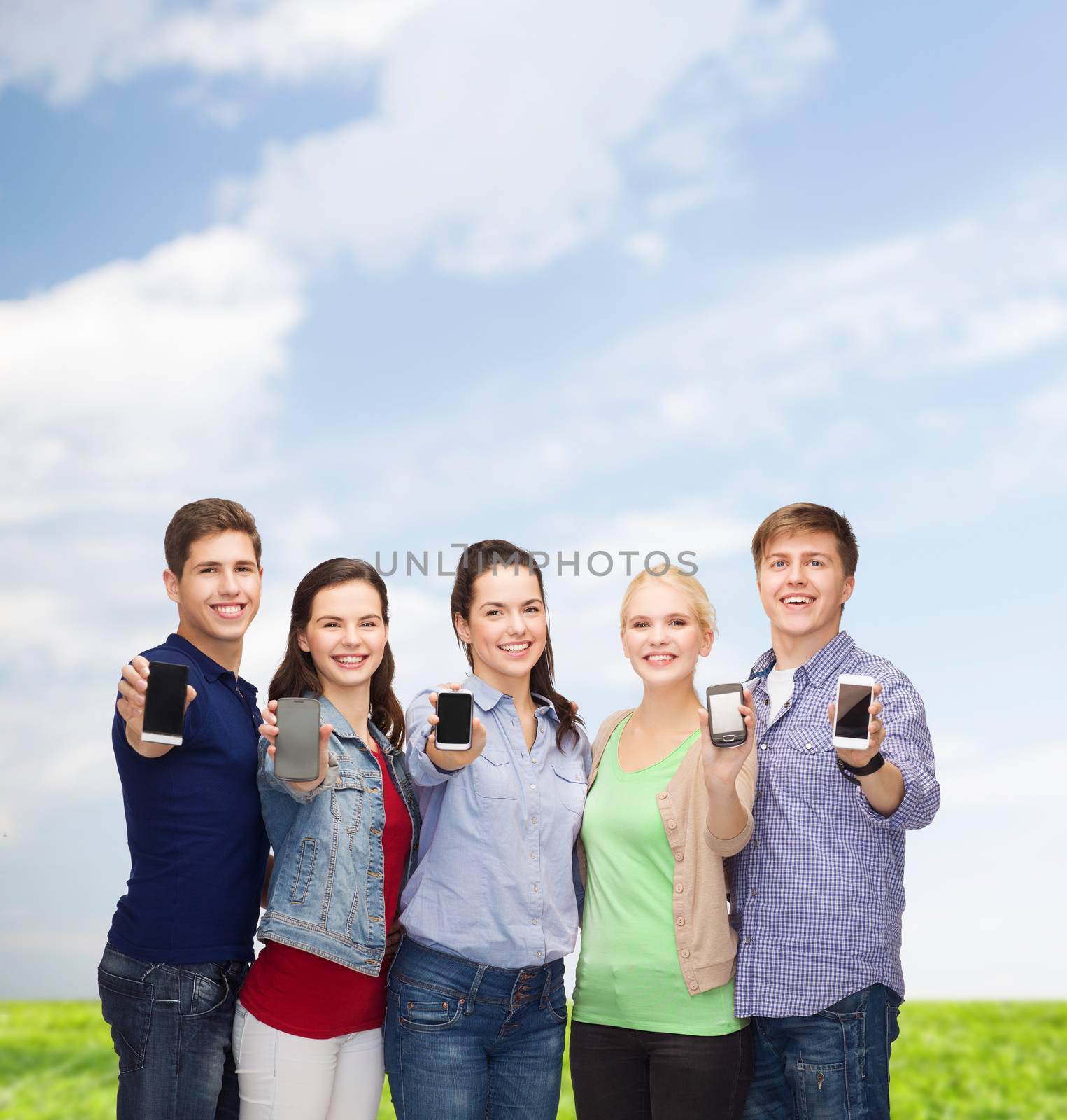 education and modern technology concept - smiling students showing blank smartphones screens