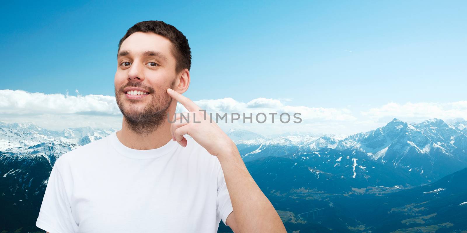 health and beauty concept - smiling young handsome man pointing to cheek