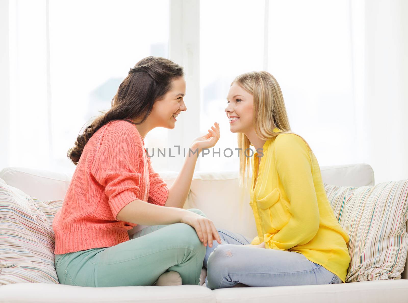 friendship and happiness concept - two girlfriends having a talk at home