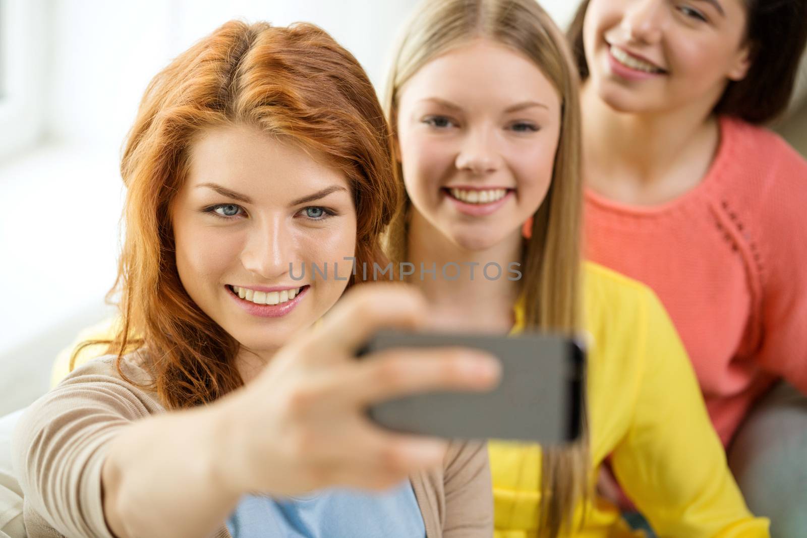 smiling teenage girls with smartphone at home by dolgachov