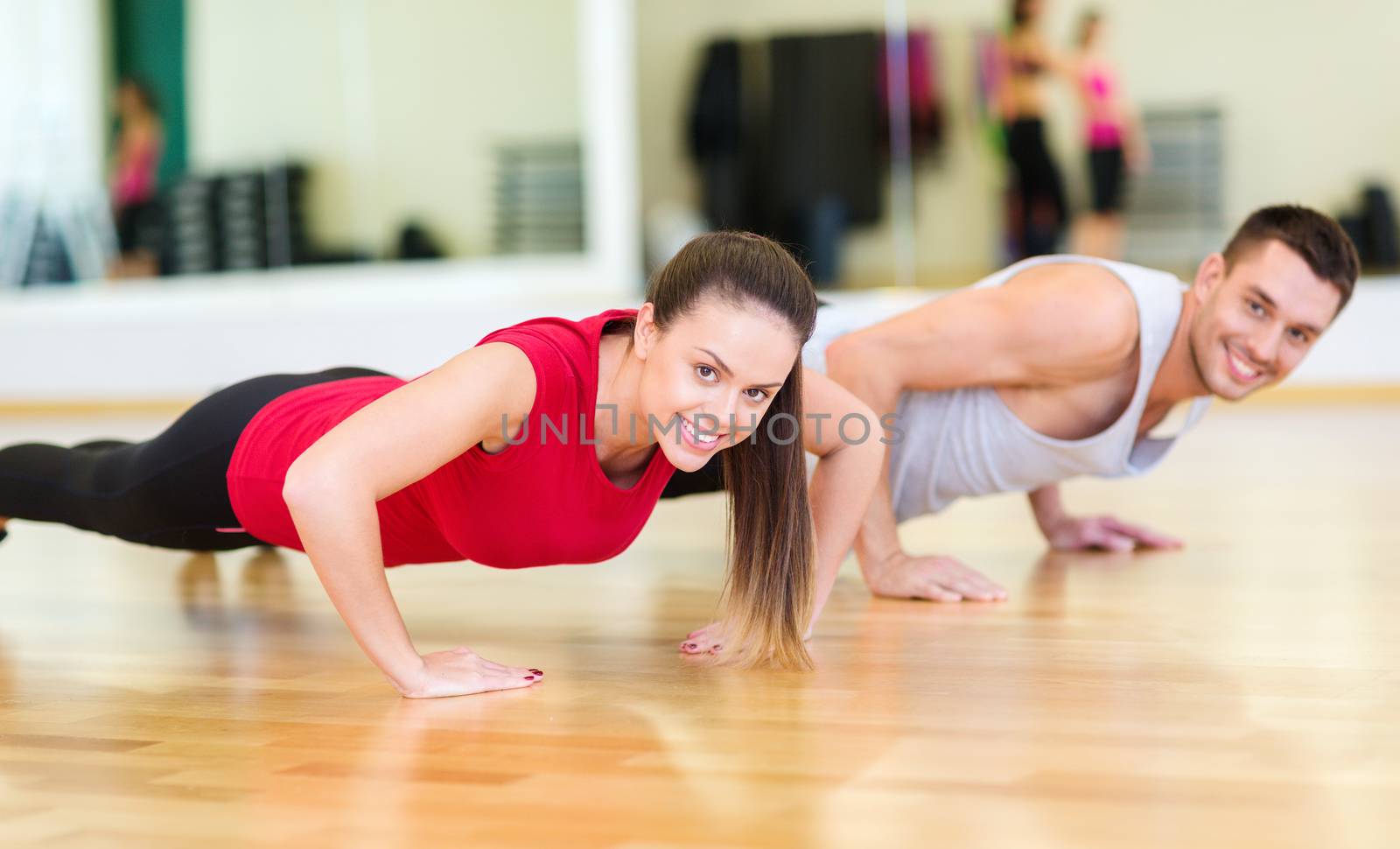 smiling couple doing push-ups in the gym by dolgachov