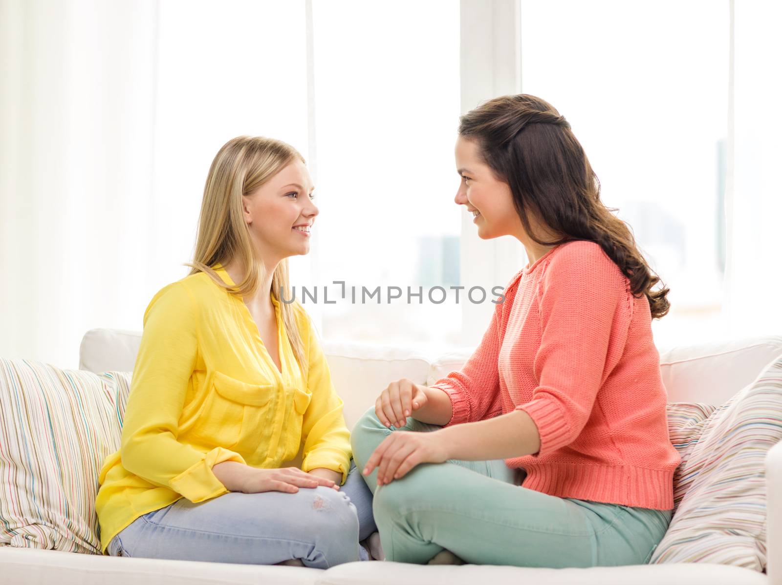 friendship and happiness concept - two girlfriends having a talk at home