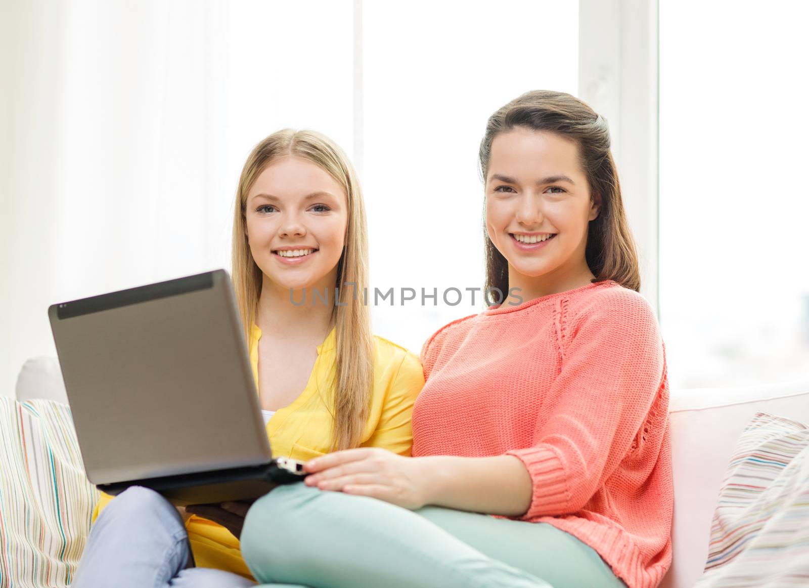 two smiling teenage girls with laptop at home by dolgachov