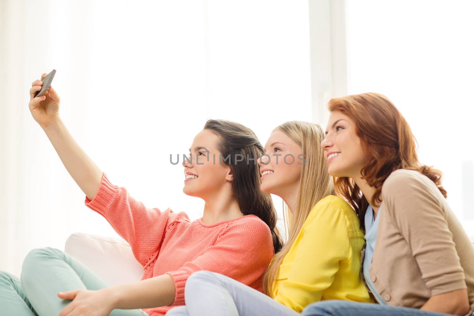 smiling teenage girls with smartphone at home by dolgachov