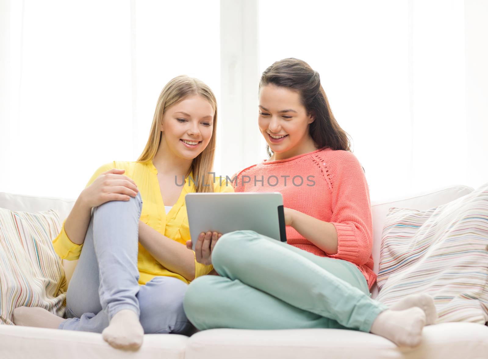 friendship, technology and internet concept - two smiling teenage girls with tablet pc computer at home