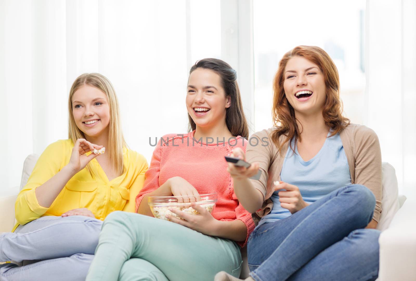 home, technology and friendship concept - three smiling teenage girl watching tv at home and eating popcorn