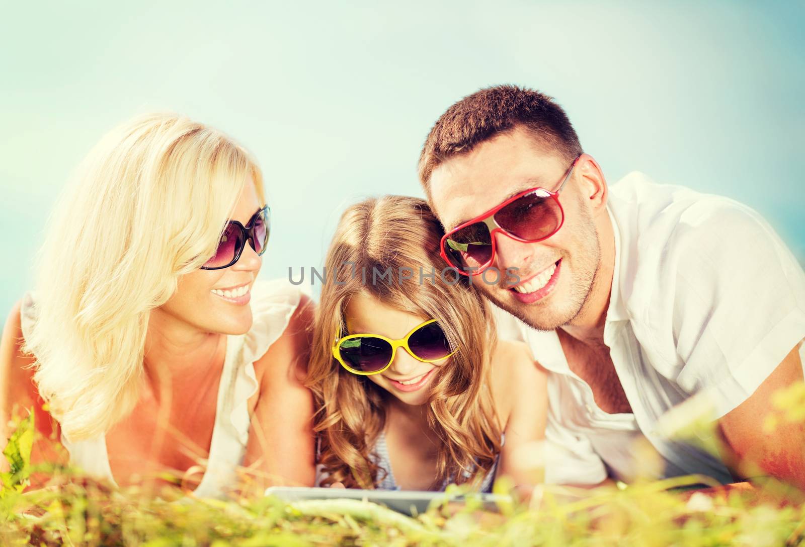 summer holidays, children and people concept - happy family with tablet pc, blue sky and green grass