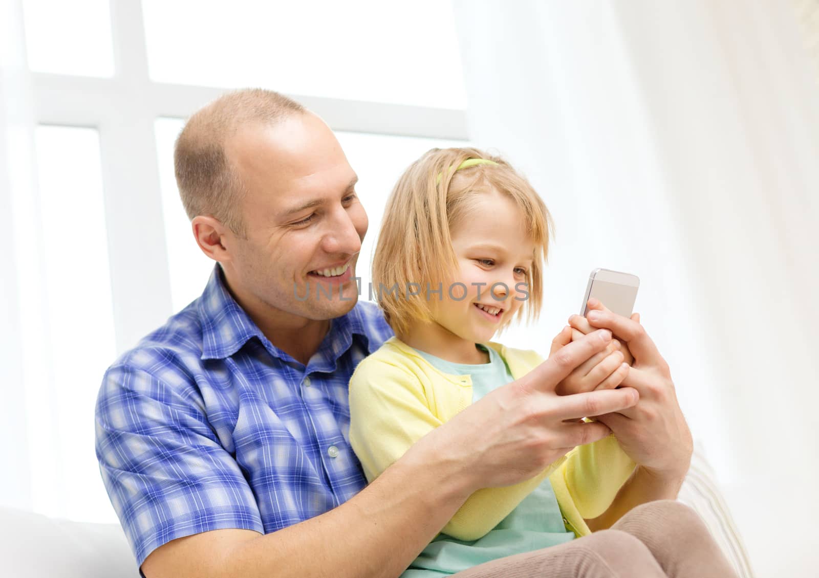 family, children, parenthood, technology and internet concept - happy father and daughter with smartphone at home