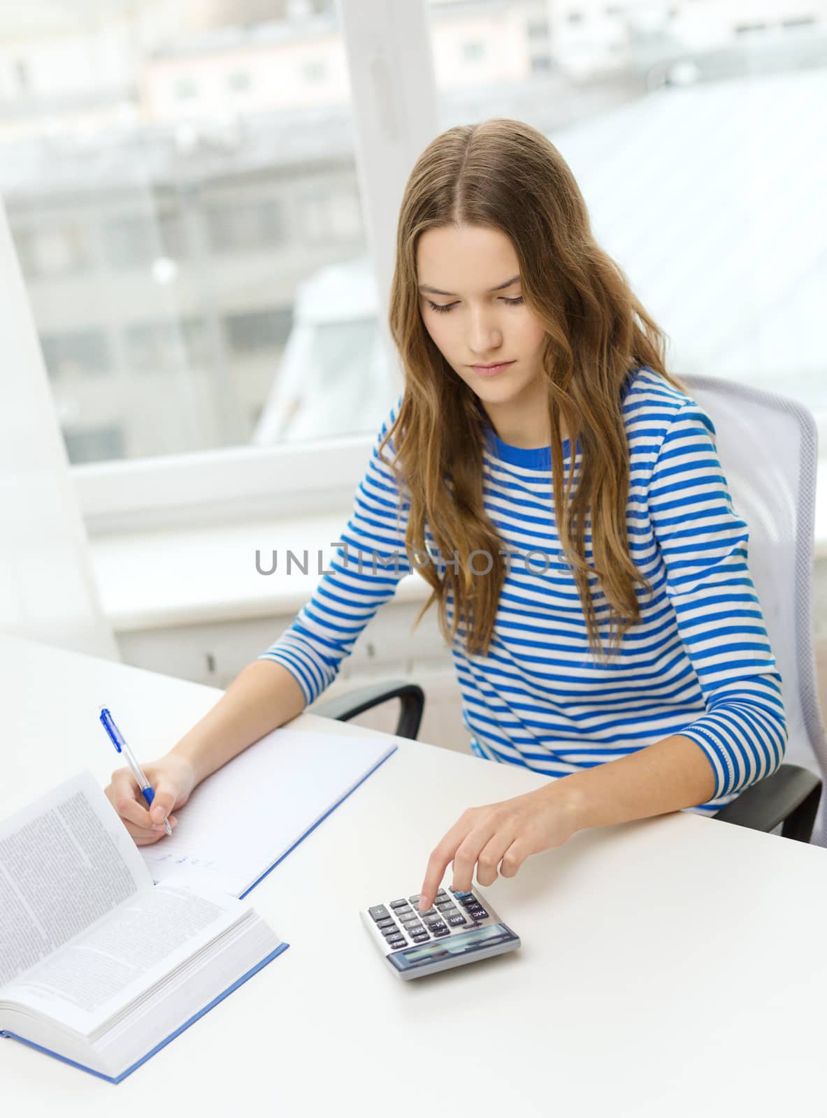 education and home concept - concentrated student girl with notebook, calculator and book