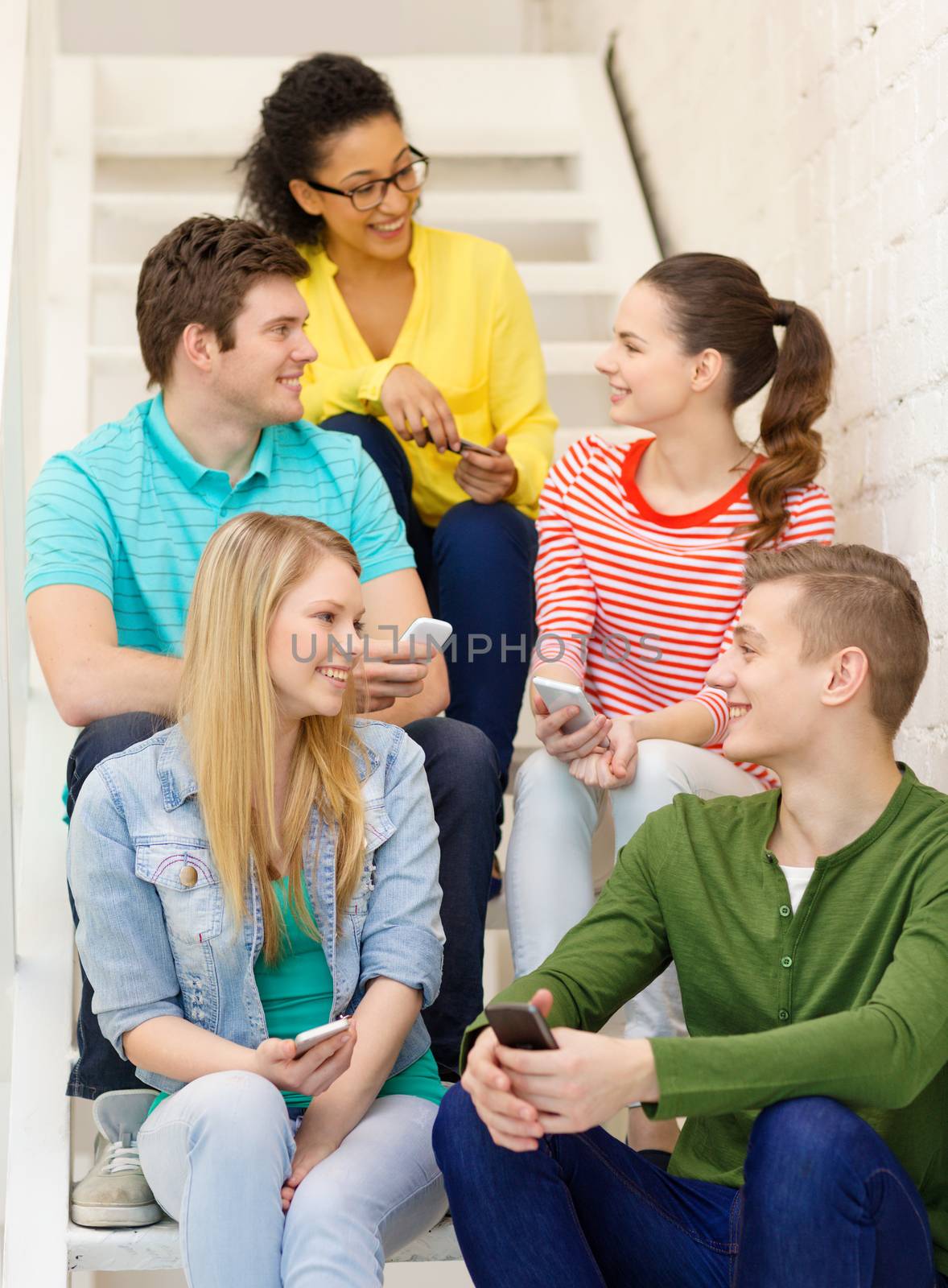 education, school and technology concept - smiling students with smartphone having discussion at school