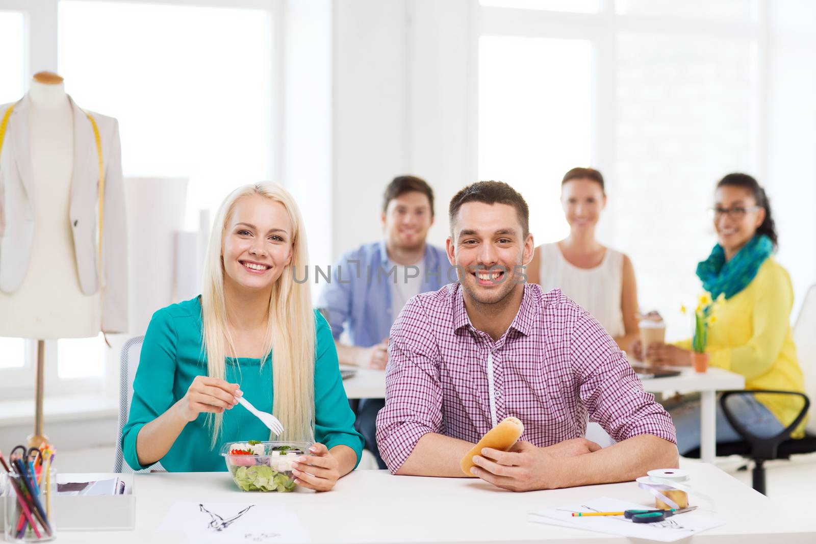 smiling fashion designers having lunch at office by dolgachov