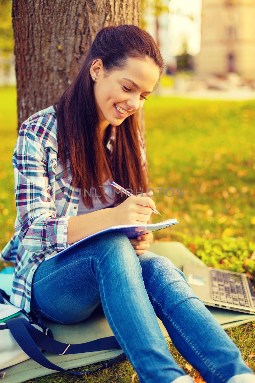 smiling teenager writing in notebook by dolgachov
