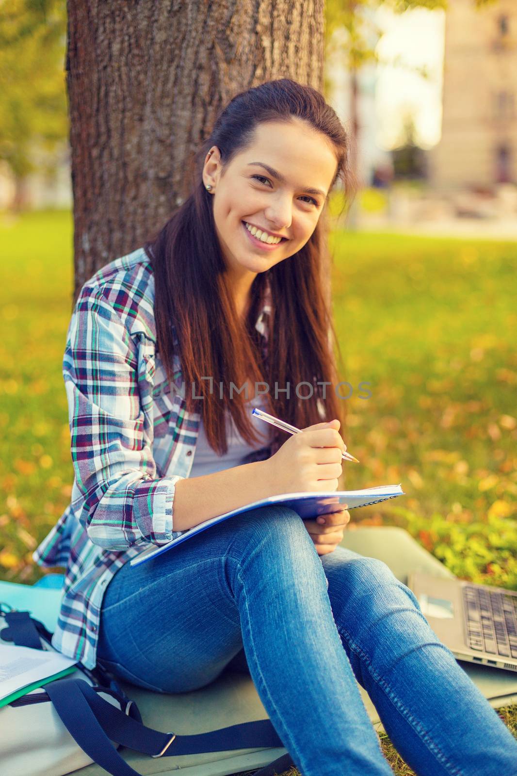 education, campus and people concept - smiling teenager writing in notebook