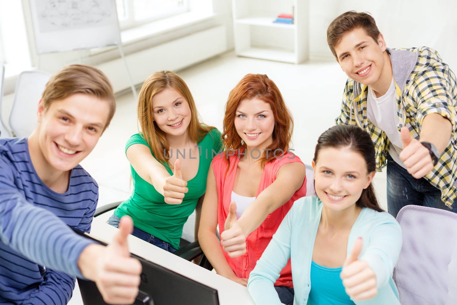 education, technology, school and people concept - group of smiling students showing thumbs up in computer class at school