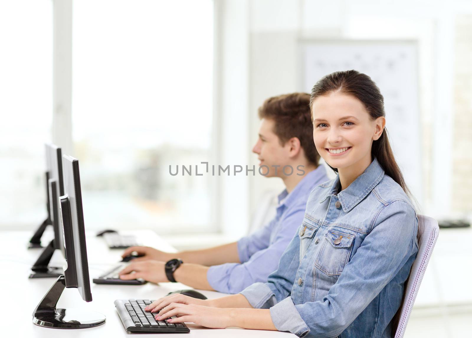 education, technology and school concept - two smiling students in computer class