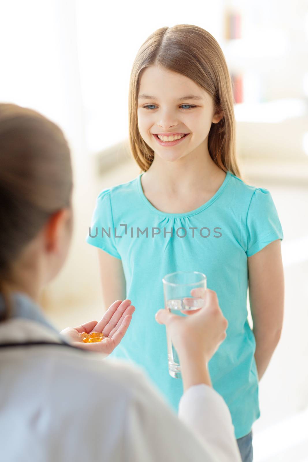 healthcare, child and medical concept - female doctor giving pills and water to little girl in hospital