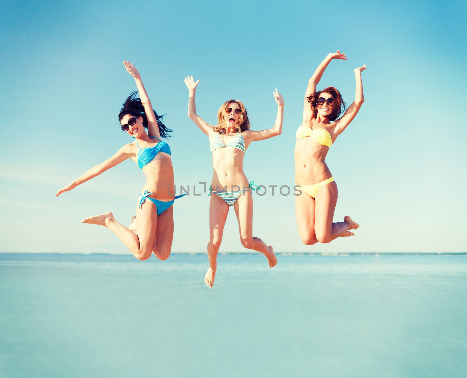 summer holidays and vacation - girls jumping on the beach