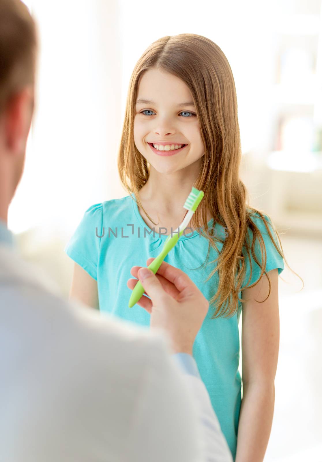 male doctor giving toothbrush to smiling girl by dolgachov