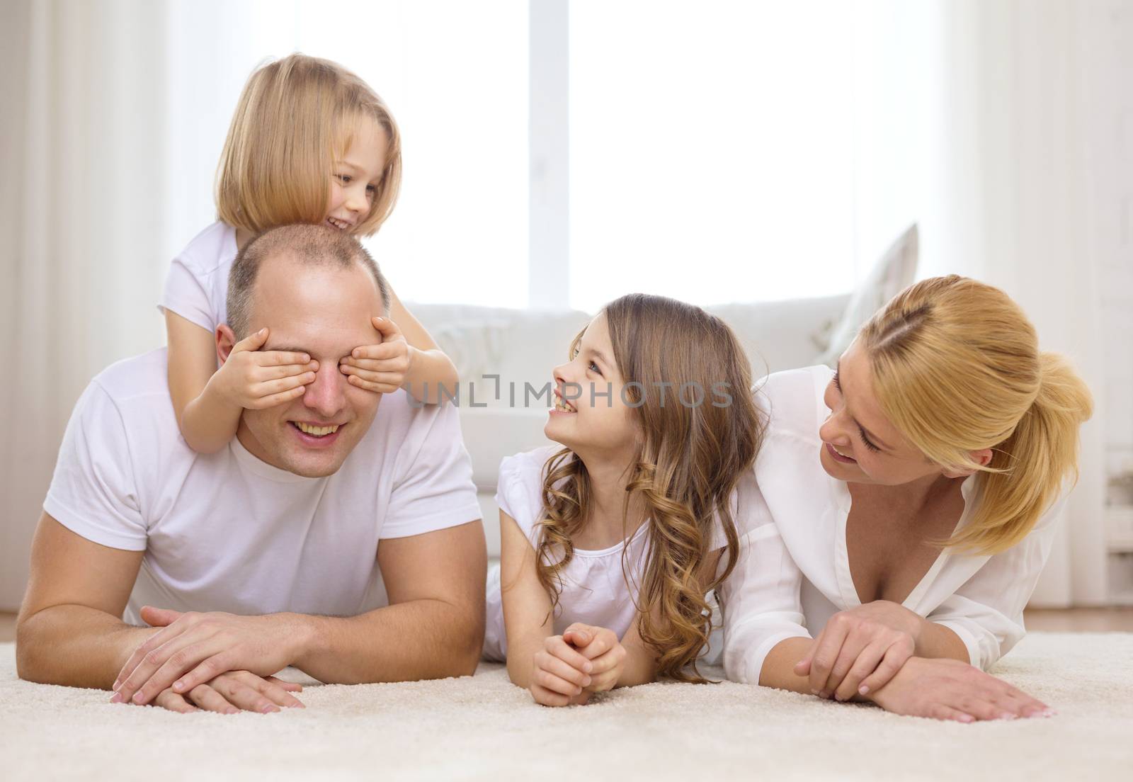 family, children and home concept - smiling family with and two little girls lying on floor at home and having fun