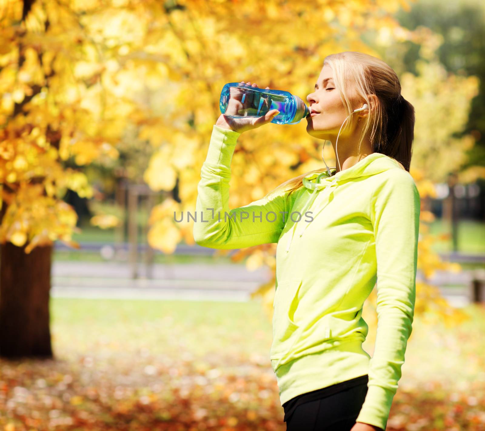 woman drinking water after doing sports outdoors by dolgachov