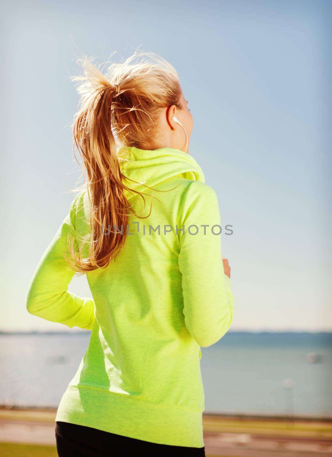 sport, fitness, exercise and lifestyle concept - woman doing running with earphones outdoors