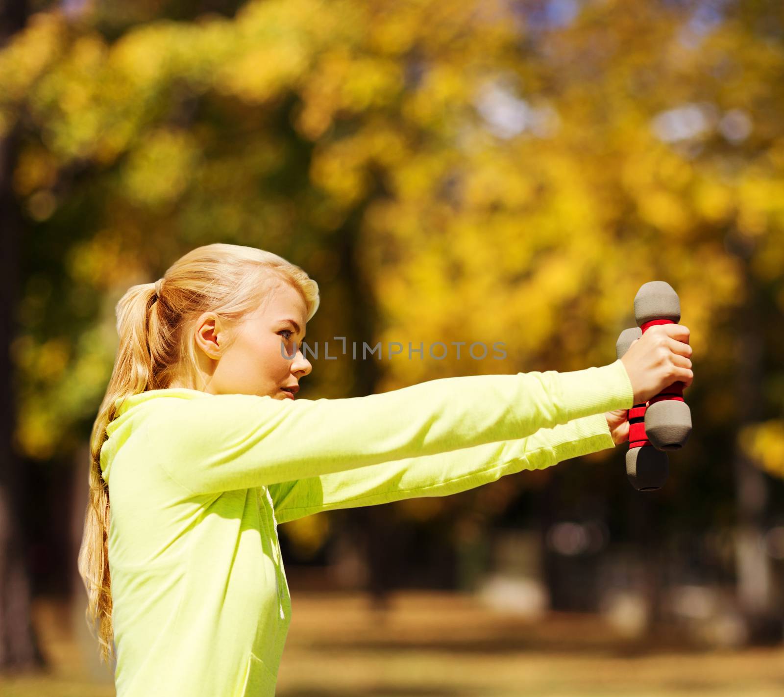 sporty woman with light dumbbells outdoors by dolgachov