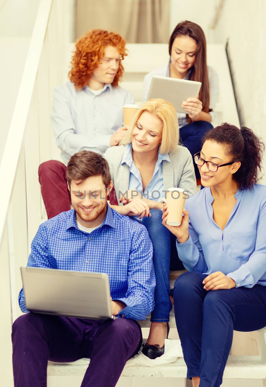 team with laptop and tablet pc on staircase by dolgachov