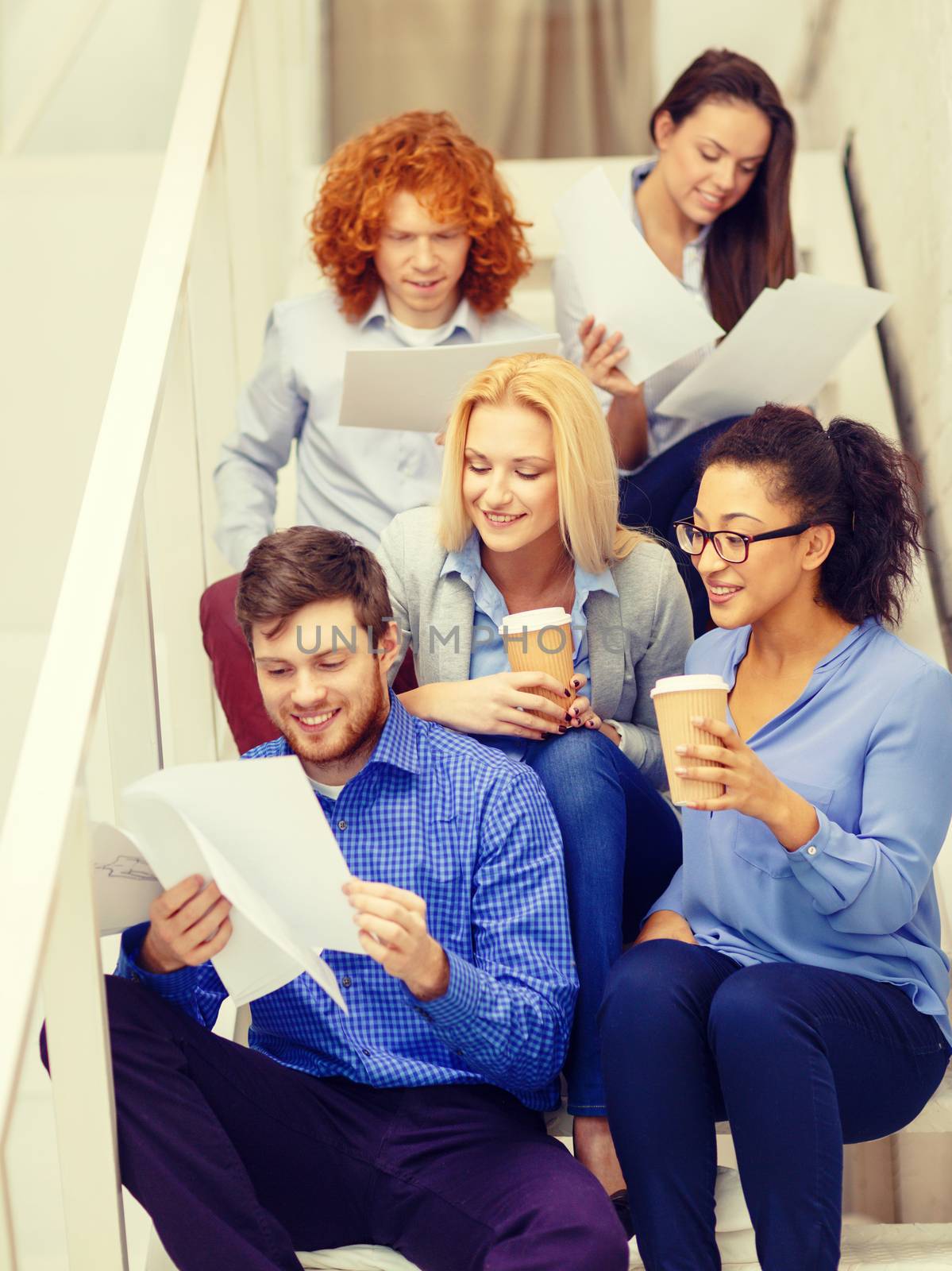 team with papers and take away coffee on staircase by dolgachov