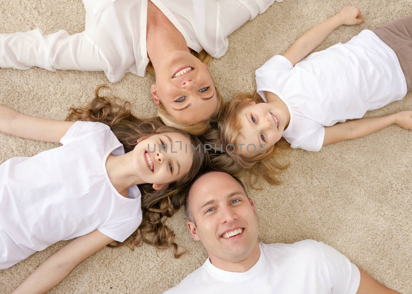 parents and two girls lying on floor at home by dolgachov