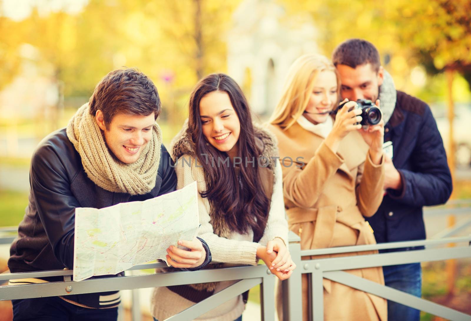 holidays and tourism concept - group of friends or couples with tourist map and camera in autumn park