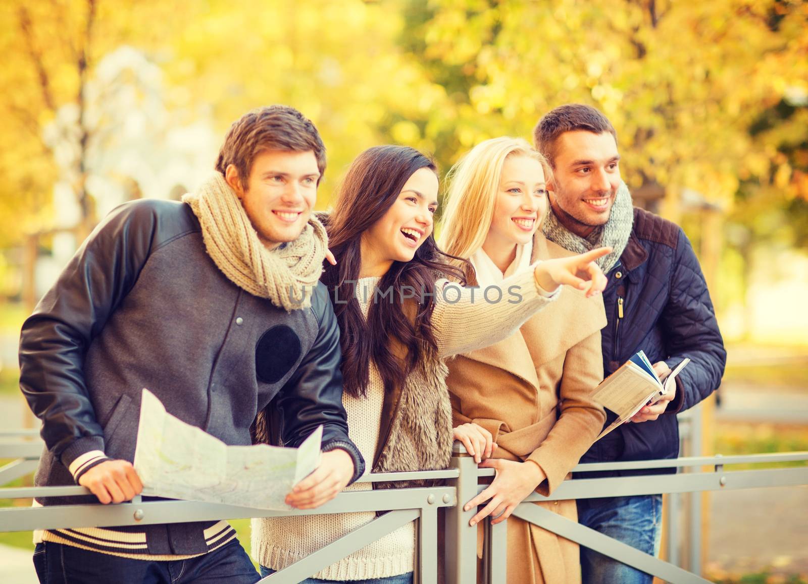 holidays and tourism concept - group of friends or couples with tourist map in autumn park