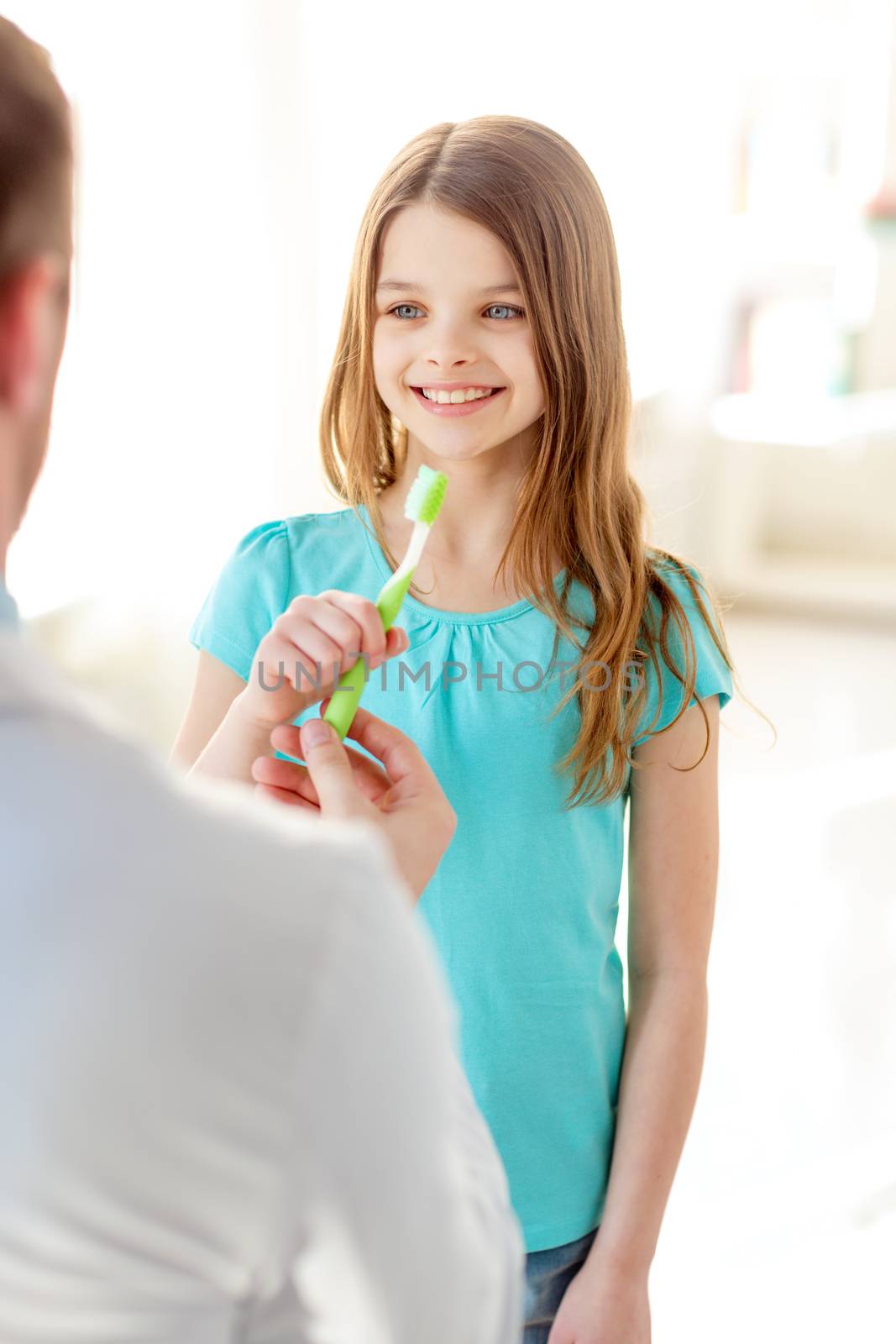 male doctor giving toothbrush to smiling girl by dolgachov