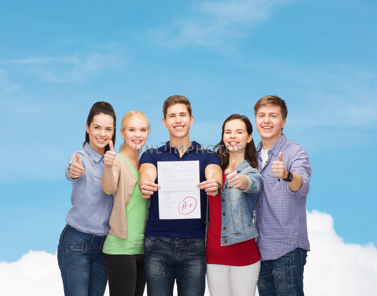 education and people concept - group of smiling students standing and showing test and thumbs up over blue sky background