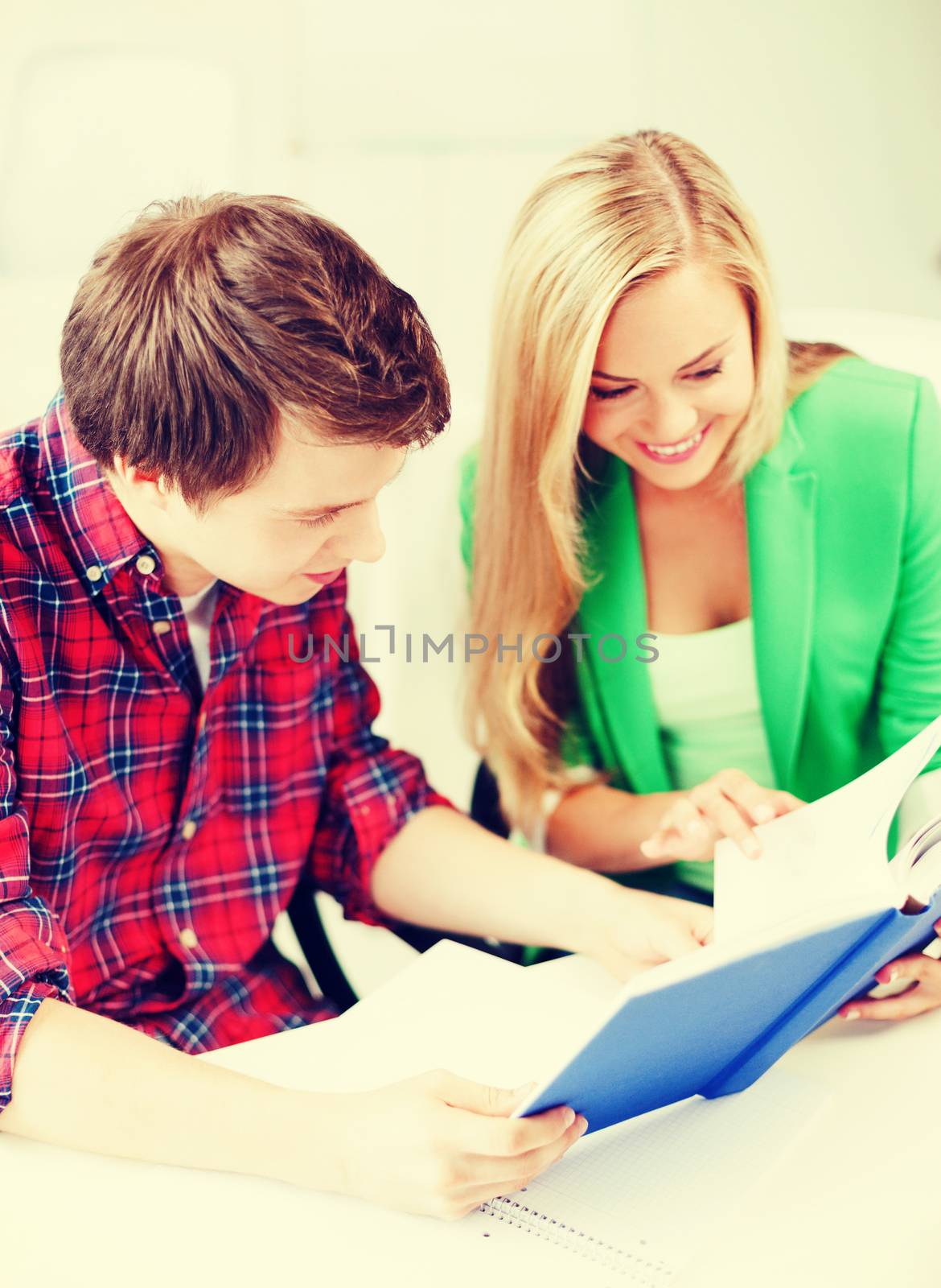 education concept - smiling students reading book at school