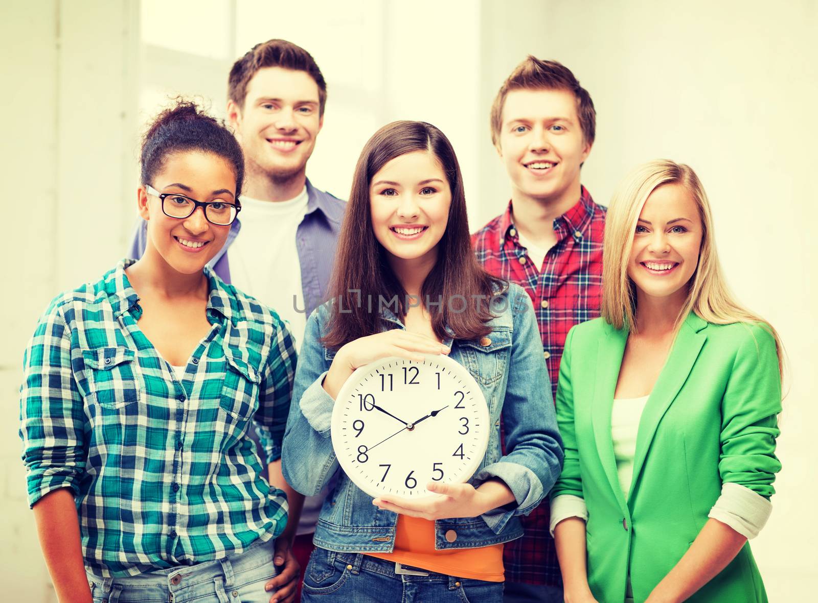 education and time concept - group of students at school with clock