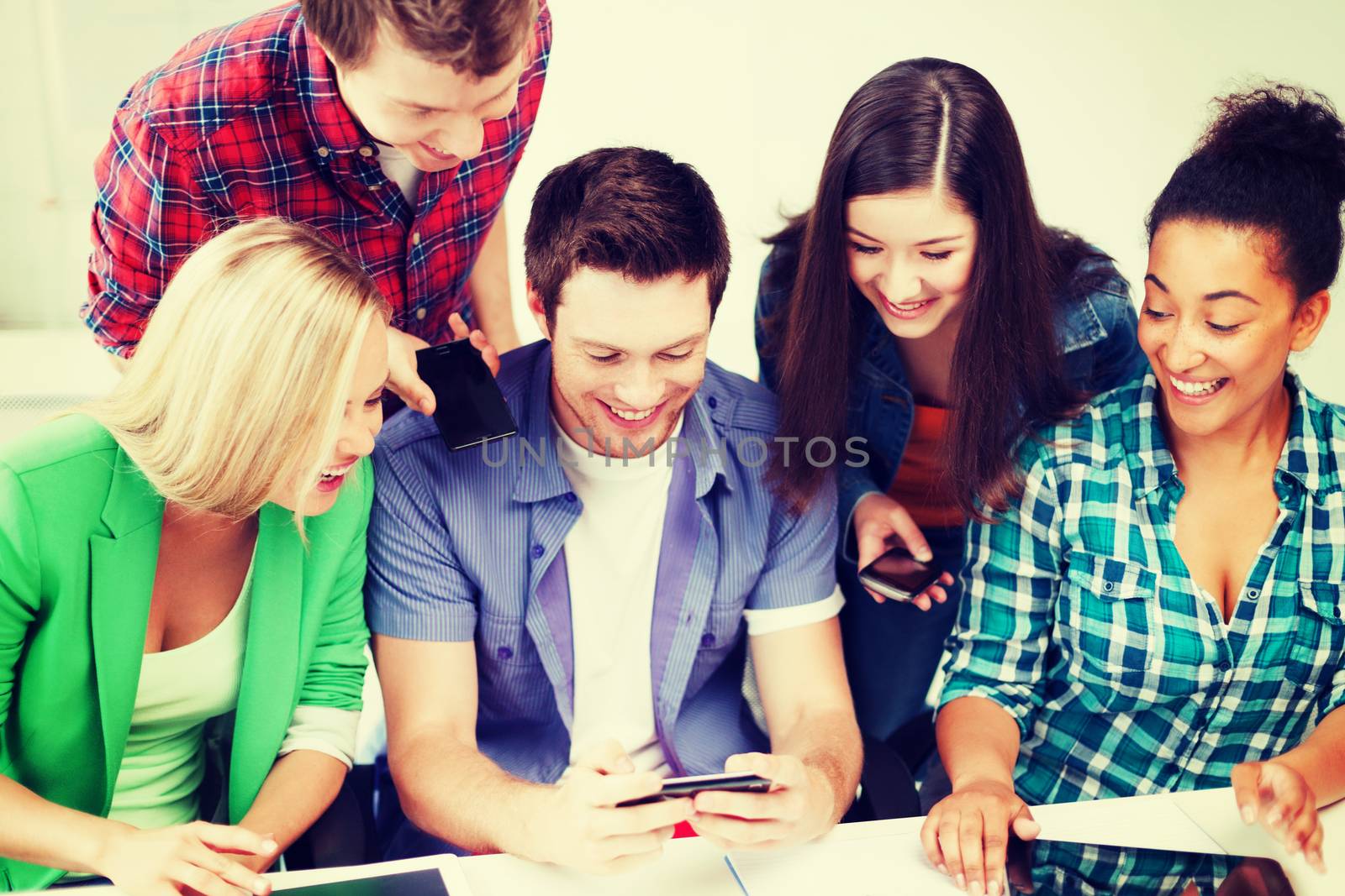 education concept - group of students looking into smartphone at school