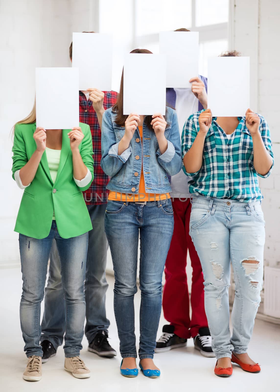 students covering faces with blank papers by dolgachov