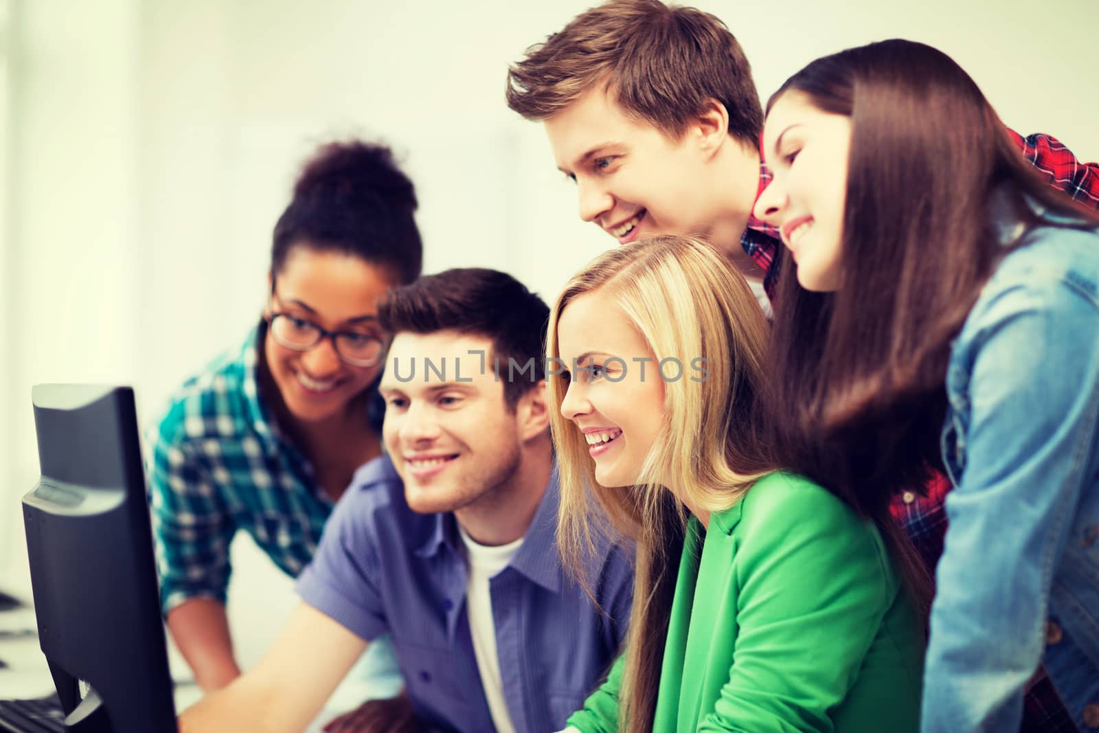 students looking at computer monitor at school by dolgachov