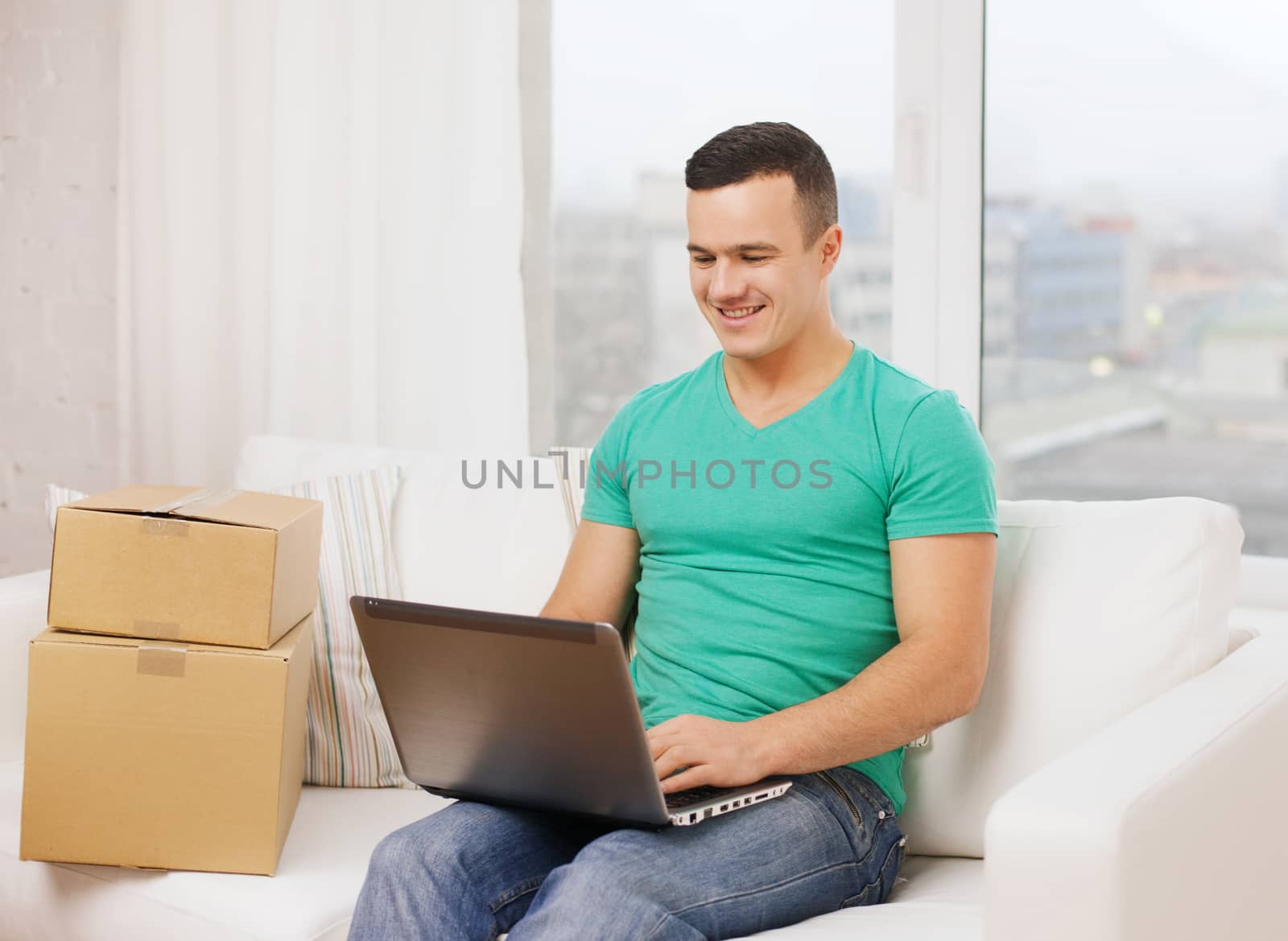 man with laptop and cardboard boxes at home by dolgachov