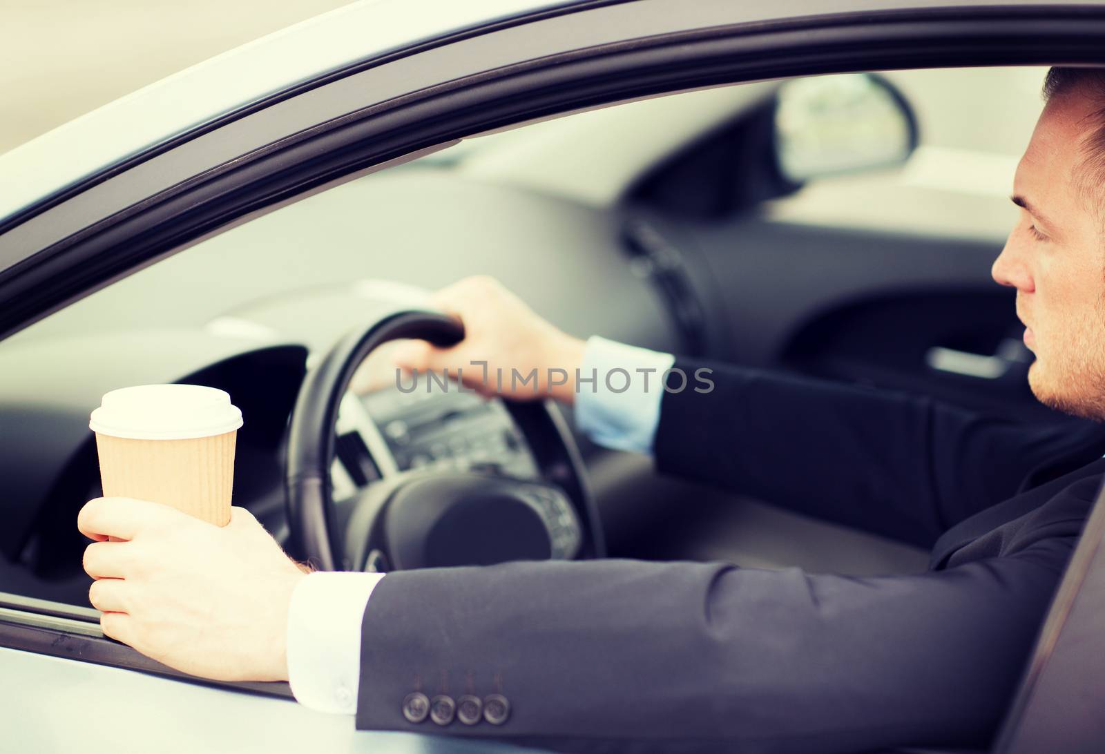 man drinking coffee while driving the car by dolgachov