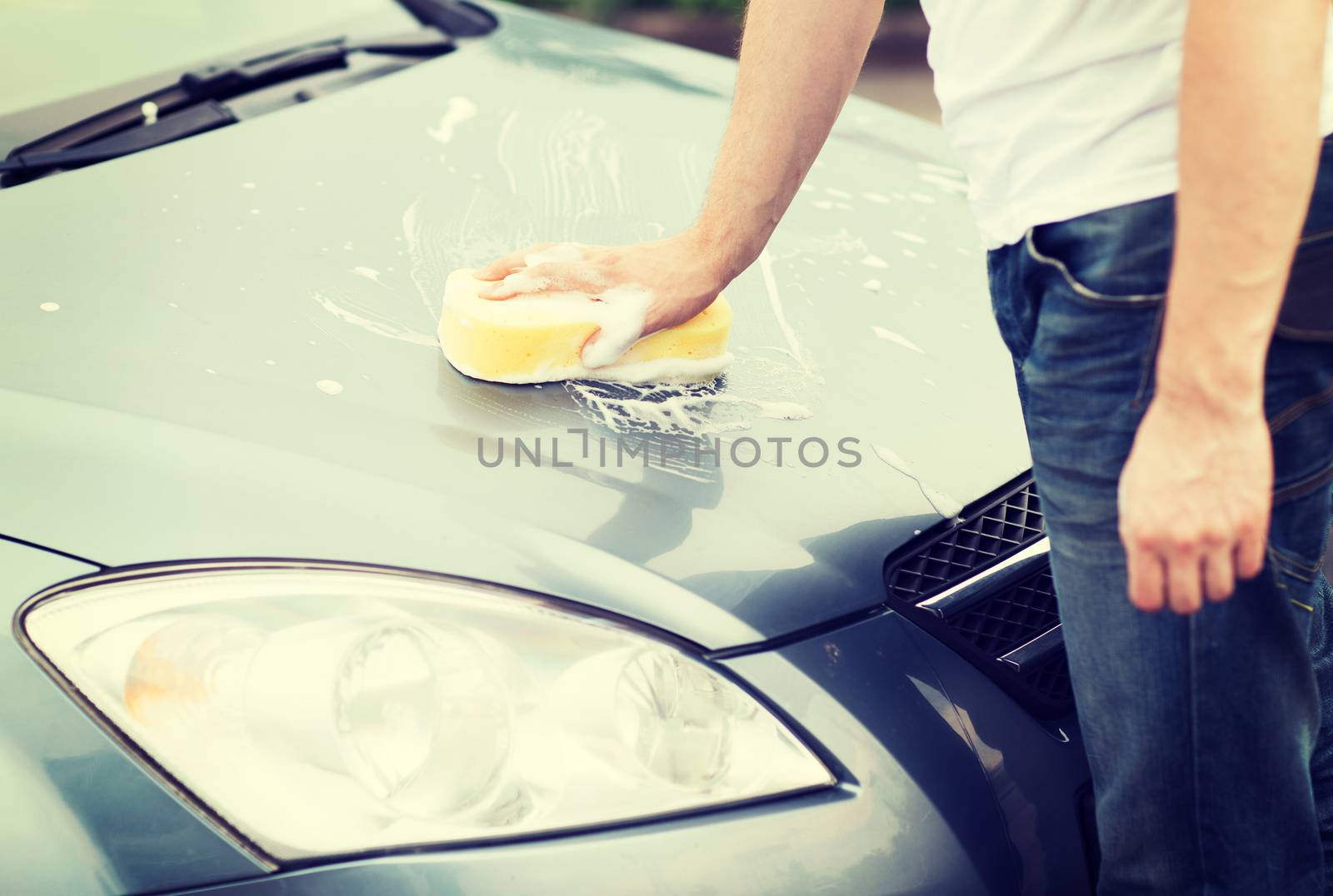 transportation and ownership concept - man washing a car