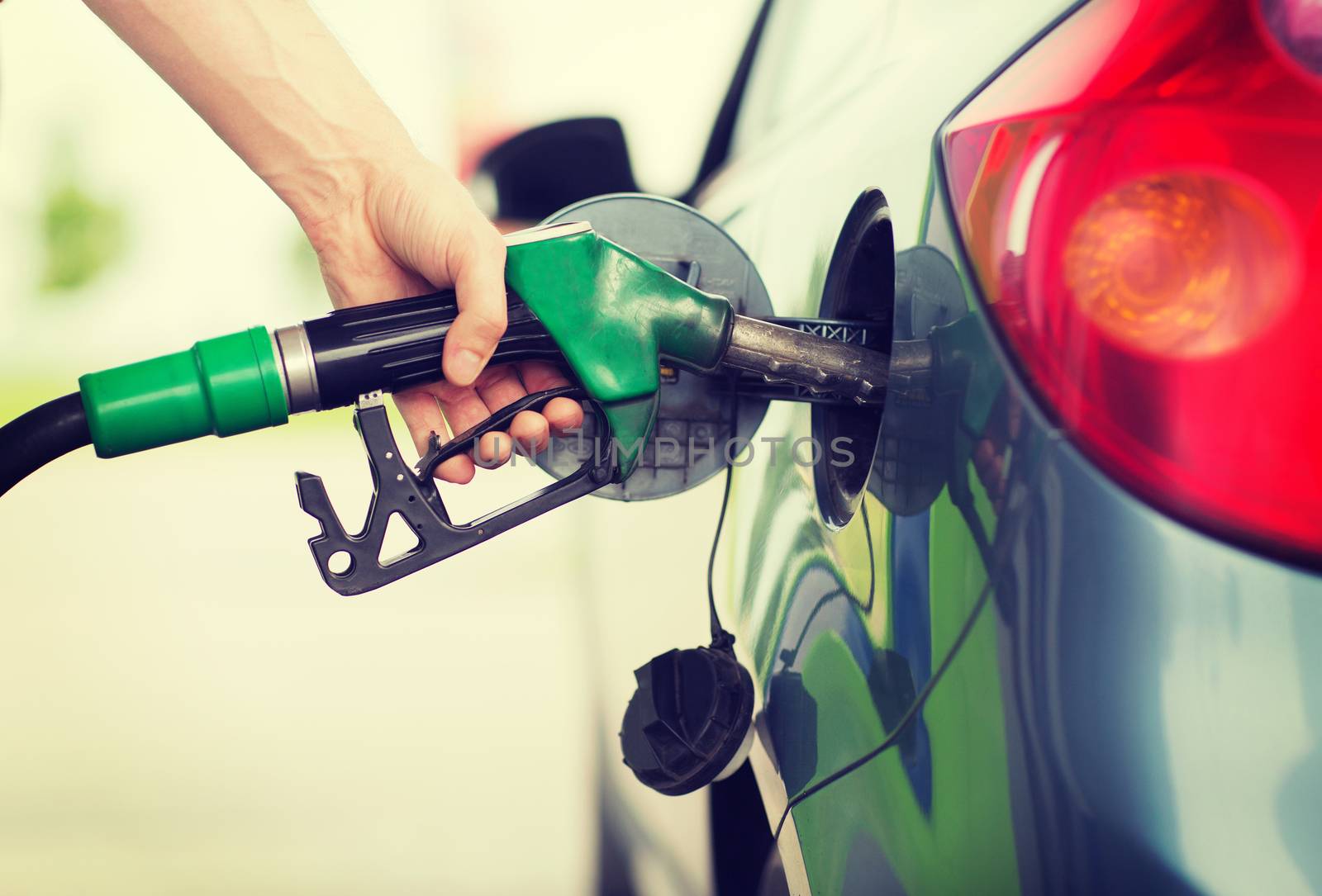 man pumping gasoline fuel in car at gas station by dolgachov