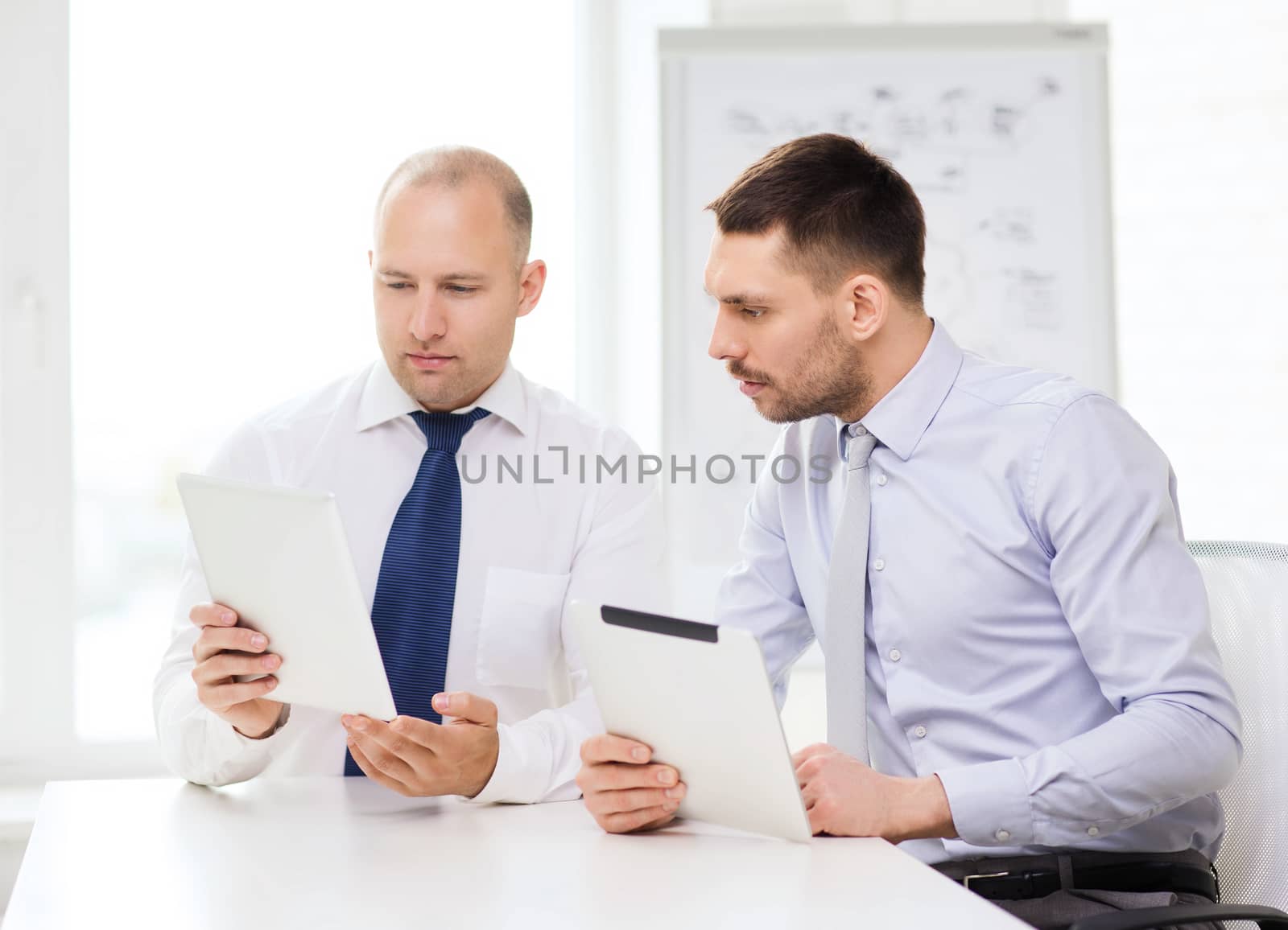 two serious businessmen with tablet pc in office by dolgachov