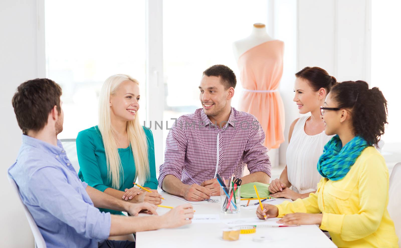 smiling fashion designers working in office by dolgachov