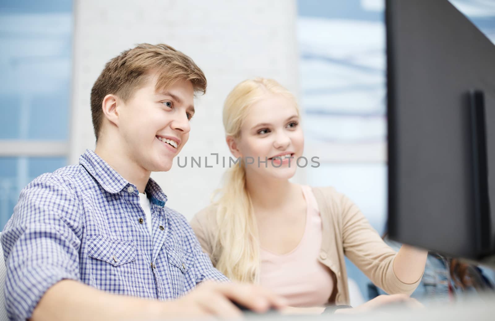 smiling teenage boy and girl in computer class by dolgachov