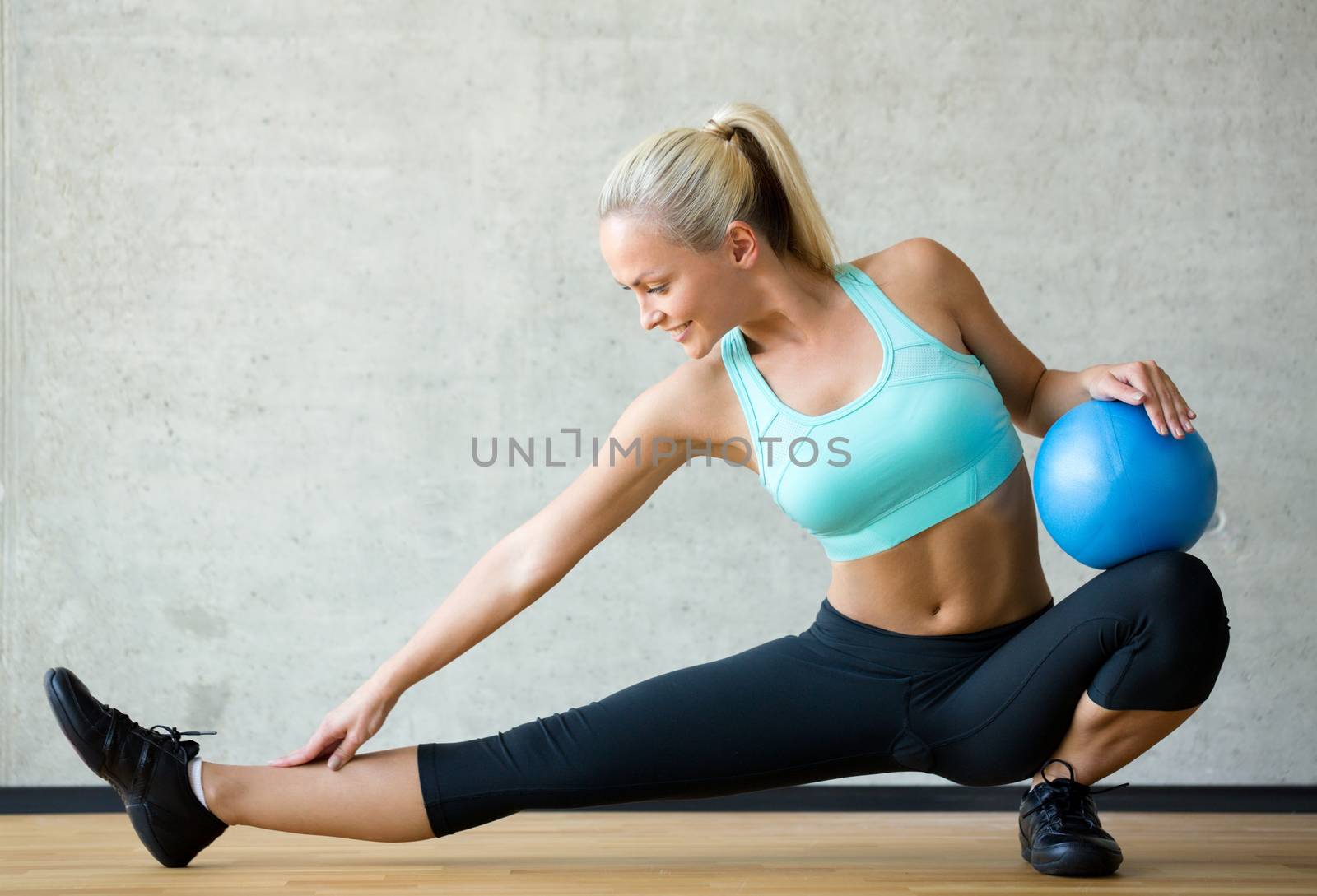 smiling woman with exercise ball in gym by dolgachov