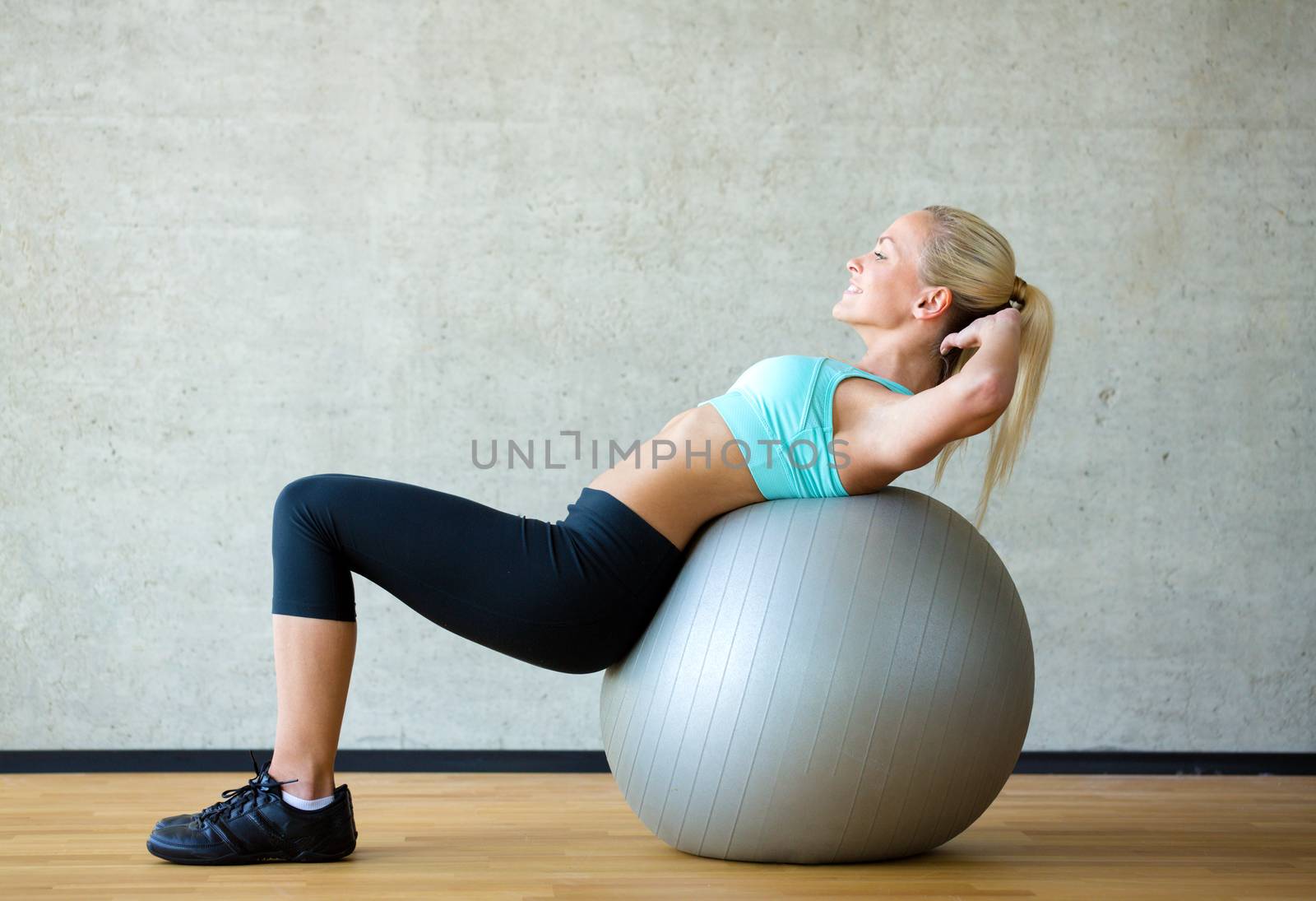 smiling woman with exercise ball in gym by dolgachov