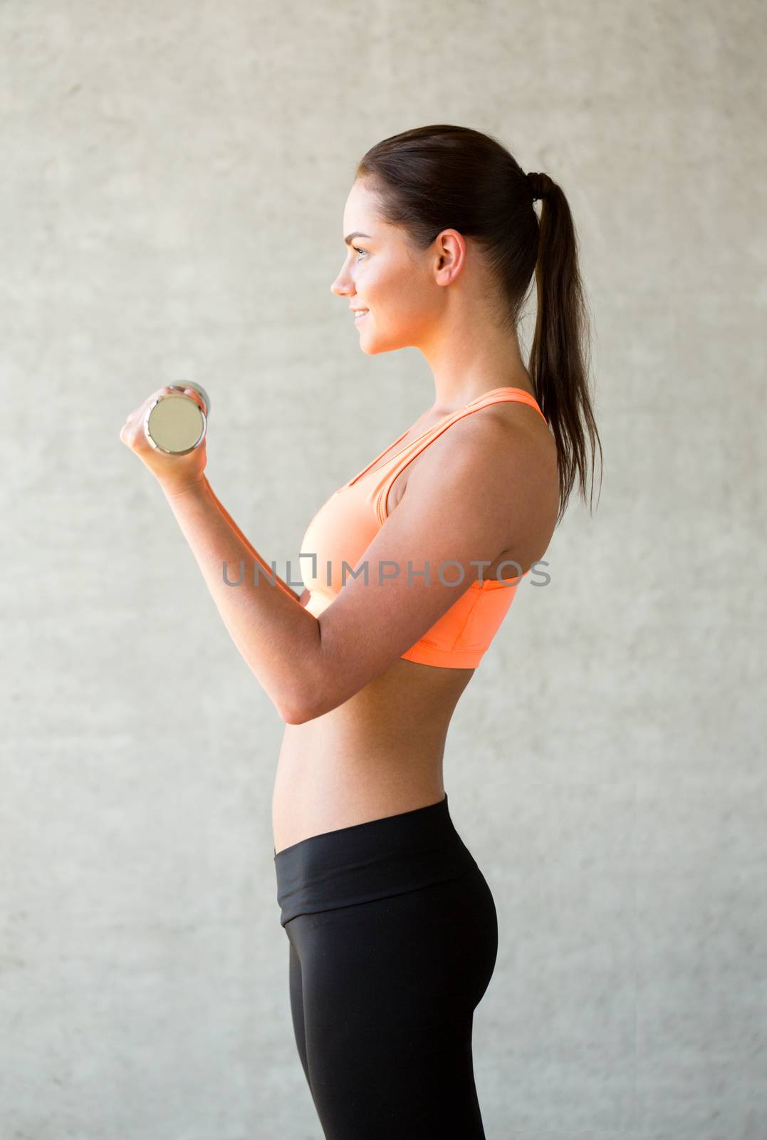 smiling woman with dumbbells in gym by dolgachov
